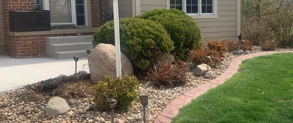 Landscape bed in Ankeny, IA, with shrubs and decorative rocks.