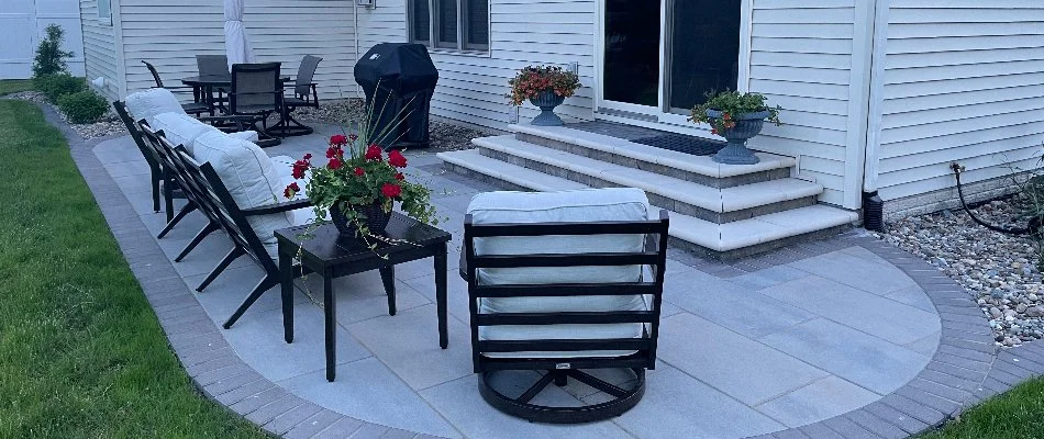 Patio in Ankeny, IA, with cushioned chairs and flowers on vases.