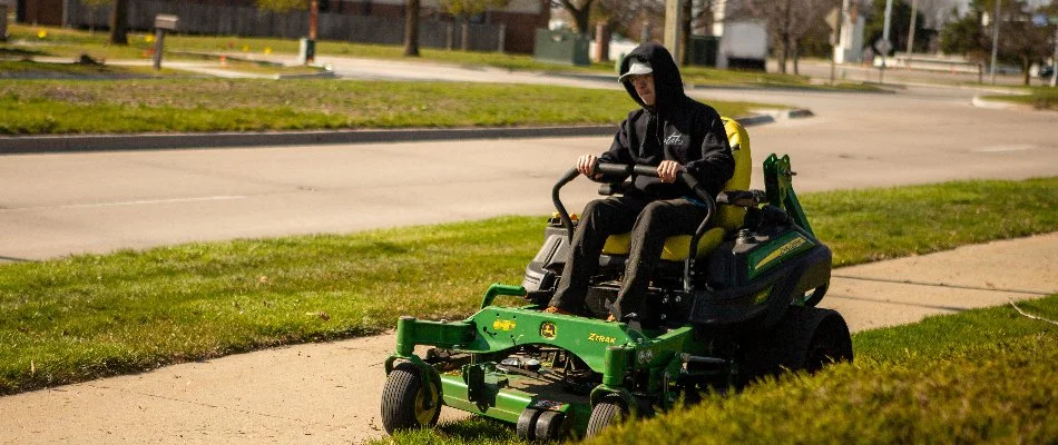 Worker mowing grass along a sidewalk in Ankeny, IA.