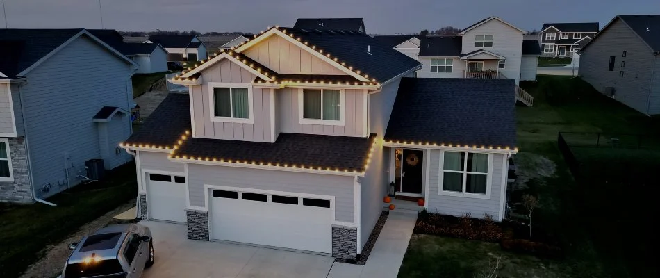 House with Christmas lights decoration on roofline at dusk in Urbandale, IA.