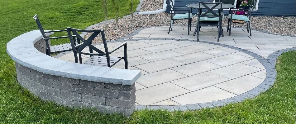 An inviting outdoor patio seating area with chairs and a table, surrounded by lush green grass and landscaped stones in Ankeny, IA.