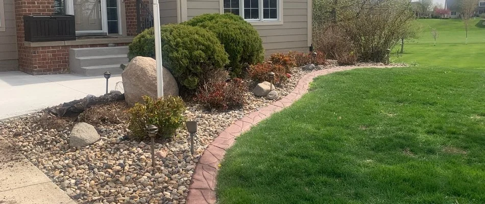 Neat lawn and landscape in Cedar Rapids, IA, with shrubs and rock ground cover.