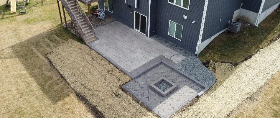 A paver patio in back of a home in Ankeny, IA, with a fire pit.