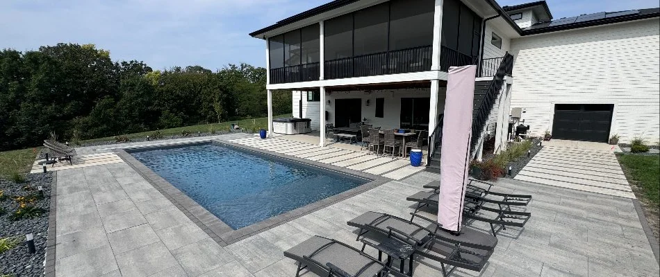 A beautiful residential pool deck with lounge chairs and a clear blue pool, surrounded by landscaped greenery in Ankeny, IA.