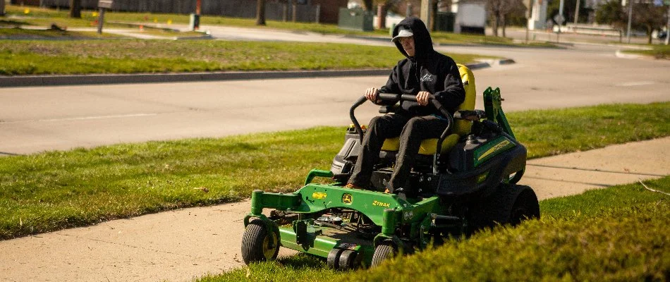 Worker mowing a lawn on a green mower in Ankeny, IA.